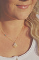 woman wearing necklace with stamped gold bar, turquoise, and shell