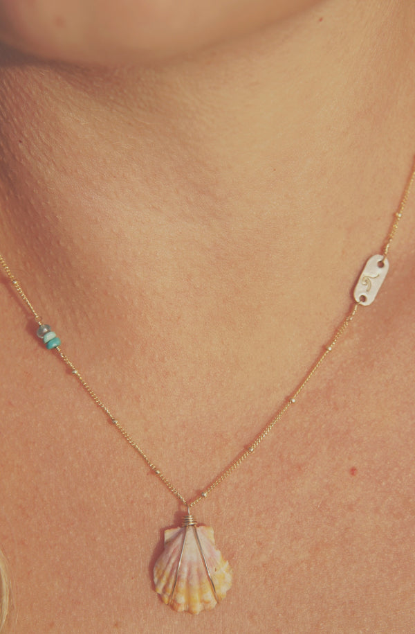 woman wearing necklace with stamped gold bar, turquoise, and shell
