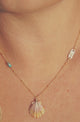 woman wearing necklace with stamped gold bar, turquoise, and shell