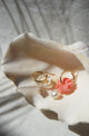 Carved coral color conch flower, freshwater pearls and nassa shell earring charms displayed in large shell