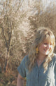 hammered gold and medium brown tassle earrings worn by woman with long blond hair