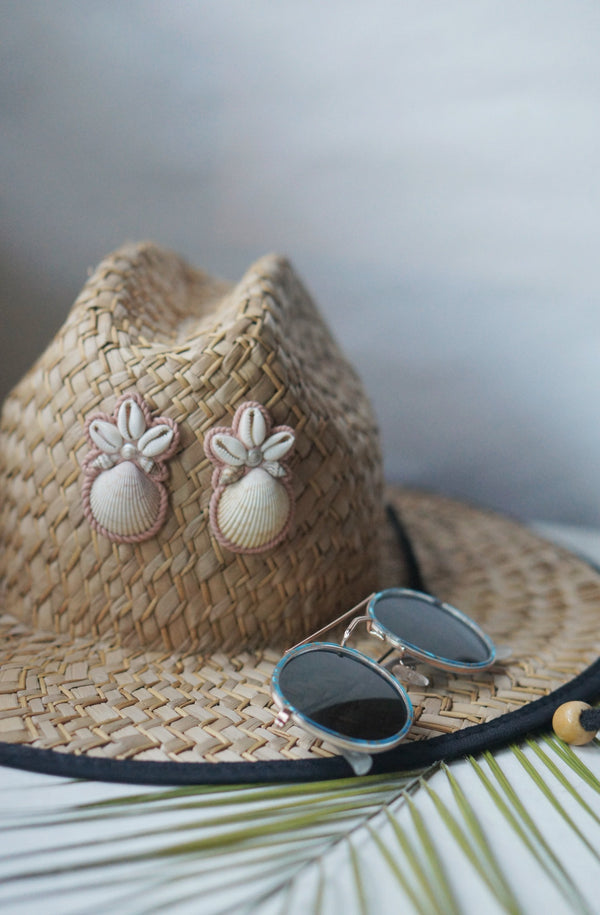 Tan and Rose pink Shell and Polymer clay earrings on a straw hat with sunglasses