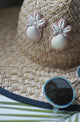 Tan and Rose pink Shell and Polymer clay earrings on a straw hat with sunglasses