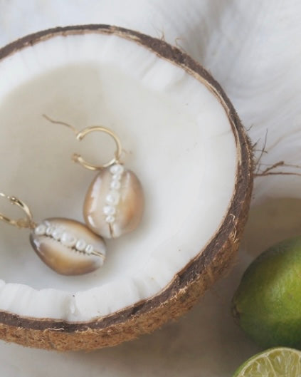 shells with pearl earring charms displayed in a coconut with limes