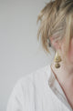 woman with blond hair wearing hammered brass earrings 