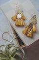 Hammered gold and mustard yellow tassle earrings on wood box