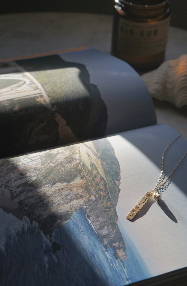 happy place necklace layed flat on an open book featuring Big Sur, California