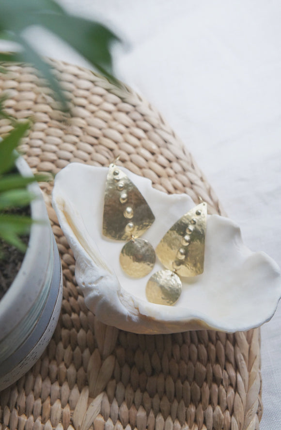 brass hammered earrings displayed in a shell