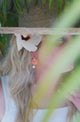 woman wearing coral colored Carved conch flower charm with hat and flower in her hair