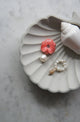 Carved coral color conch flower, freshwater pearls and nassa shell earring charms displayed in large shell